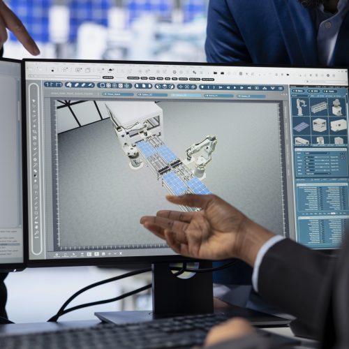 Solar energy production facility programmer writing software code on computer, developing tools to manage robotic machinery operations under supervisor surveillance, close up shot